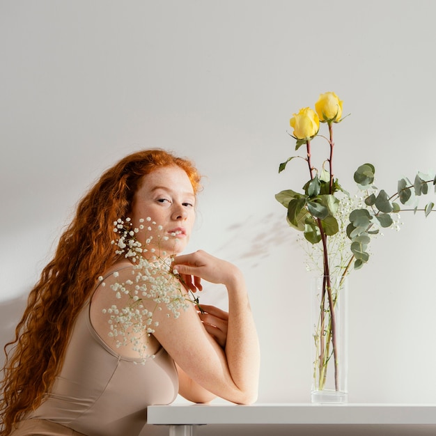 Foto vista laterale della donna con fiori di primavera in vaso sul tavolo