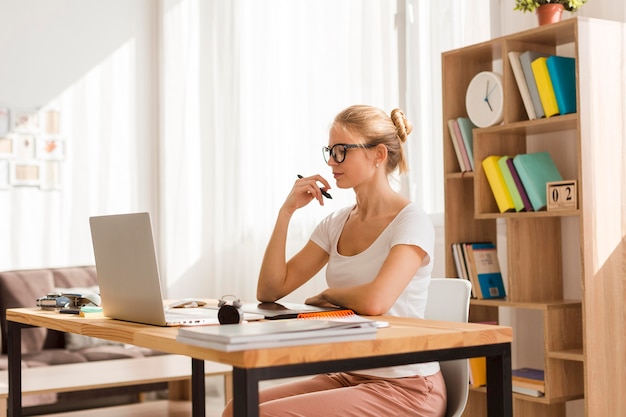 Foto vista laterale della donna che lavora al computer portatile dallo scrittorio domestico