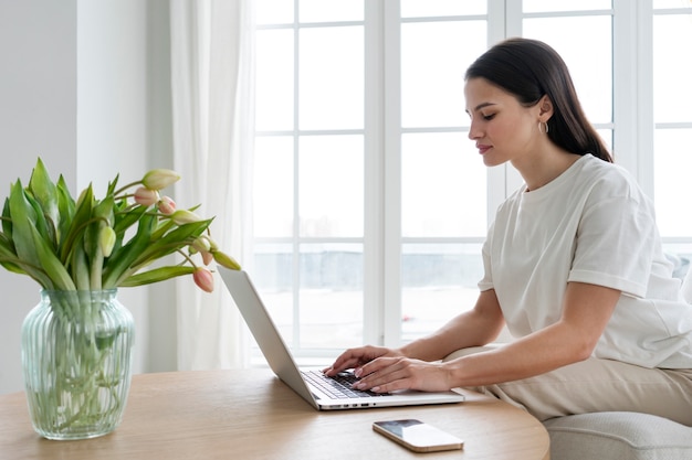 Donna di vista laterale che lavora al computer portatile