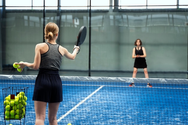 Side view women playing paddle tennis