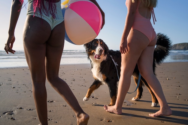 Foto donne di vista laterale che camminano sulla spiaggia con il cane