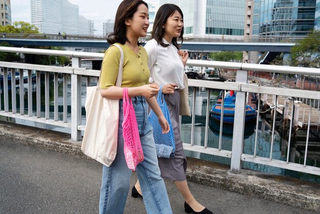 Side view women walking with tote bags