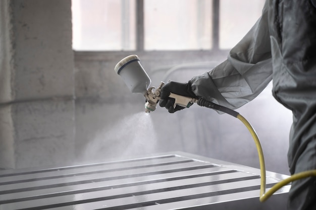 Side view worker spraying powder paint