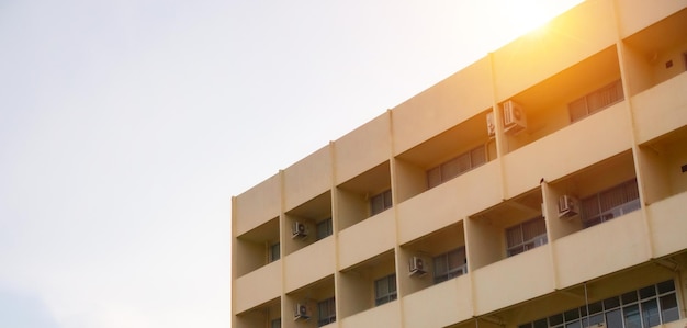 Side view of yellow concrete building Intersect the orange sun