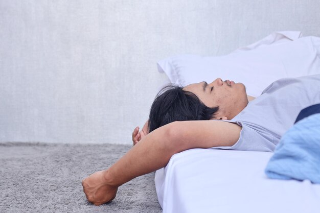 Side view of young Asian man resting and sleeping on the bed at home