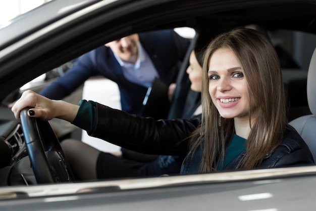 Vista laterale della giovane bella donna seduta all'interno dell'auto e che tiene la mano sul volante