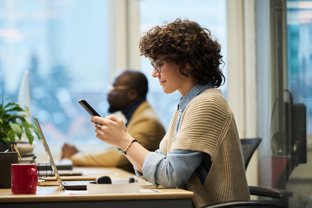 Side view of young brunette businesswoman with mobile phone