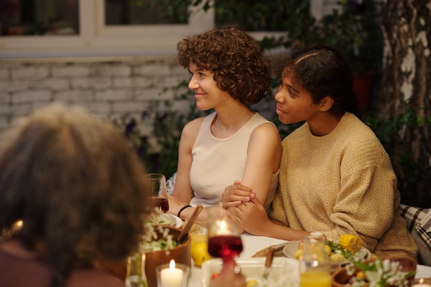 Side view of young brunette woman and her cute daughter sitting by served table