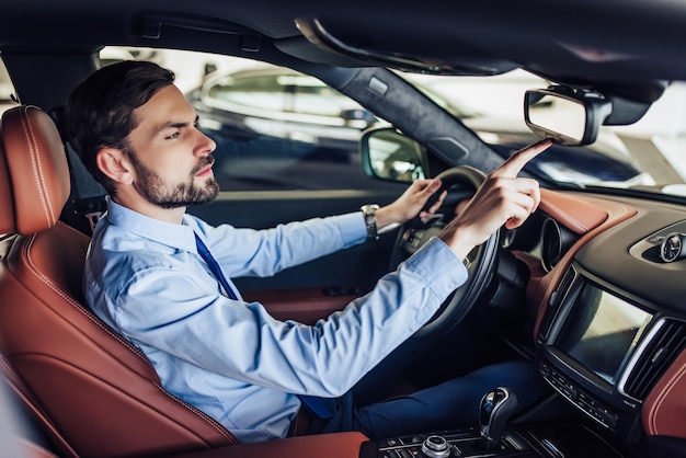 Side view of young businessman pushing button on the rear view mirror in car