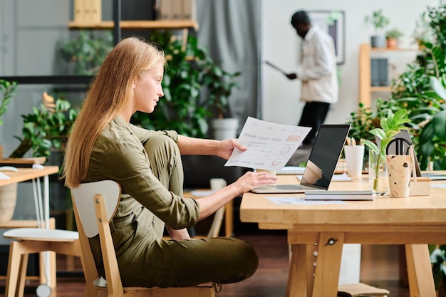 Side view of young businesswoman with long blond hair analyzing data