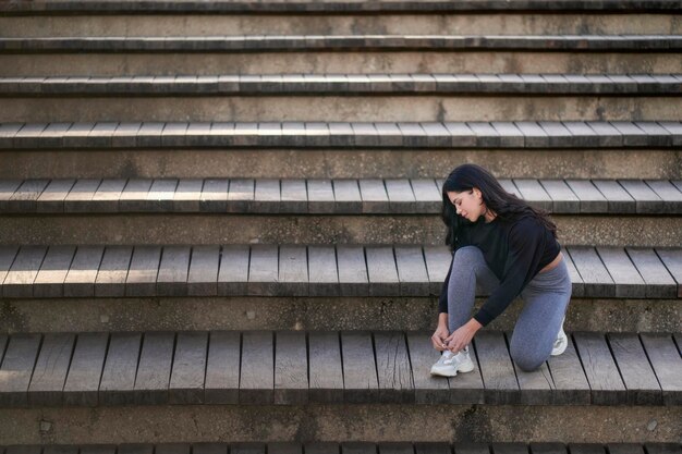 Side view of young female in casual clothes sitting on stairs\
and looking away