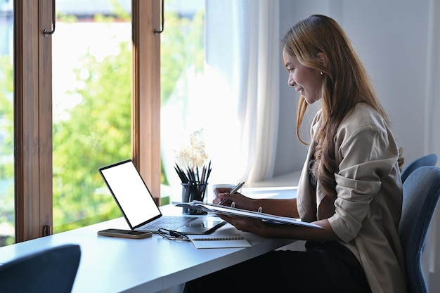 Side view young female entrepreneur working with laptop at her workplace