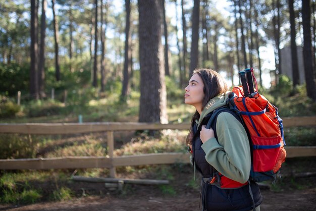 Foto vista laterale della giovane viandante. donna caucasica in abiti casual con capelli scuri e grande zaino. hobby, concetto di natura