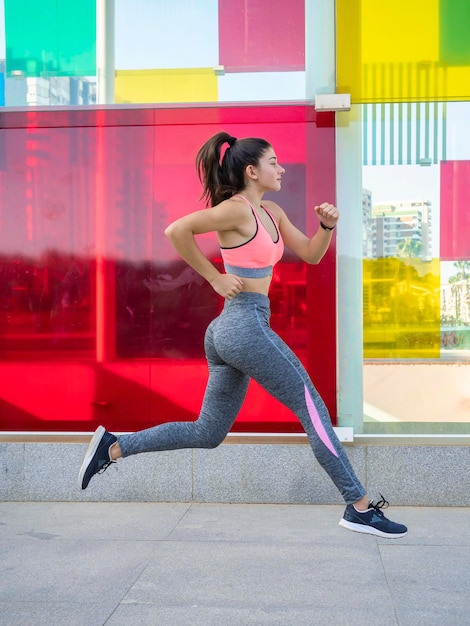 Side view of young girl training outdoors Girl running fast and powerful colorful background