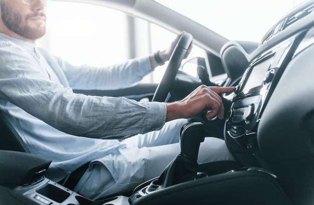 Вид сбоку на молодого красивого мужчину в формальной одежде, сидящего в новеньком автомобиле