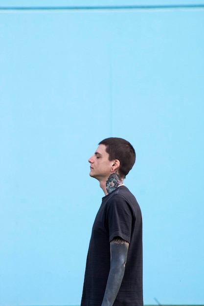 Photo side view of young man against blue wall