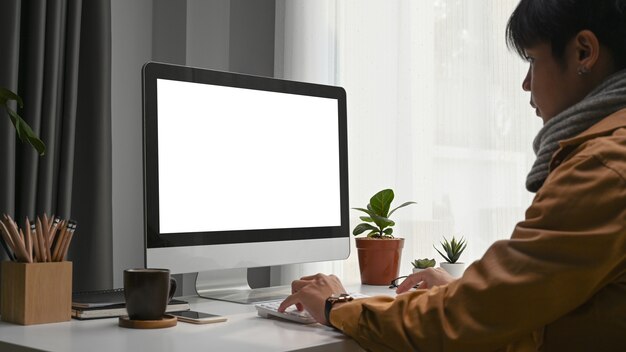 Side view of young man concentrate working online on computer while sitting at modern home office.