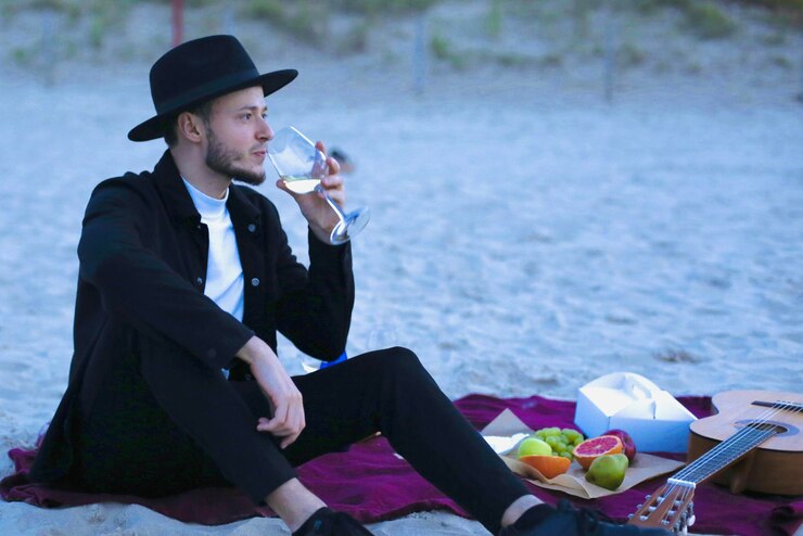 Photo side view of young man drinking wine on the beach