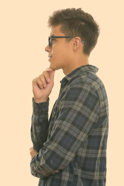 Side view of young man looking away against gray background