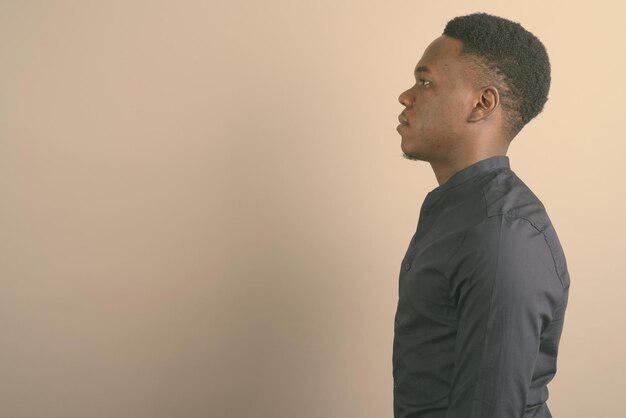 Photo side view of young man looking away against wall