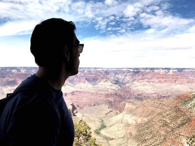 Side view of young man looking at mountain against sky