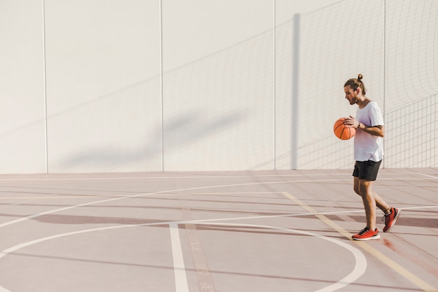 Foto vista laterale di un giovane che gioca a basket in tribunale