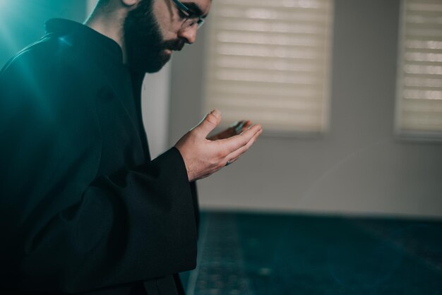 Photo side view of young man praying in mosque