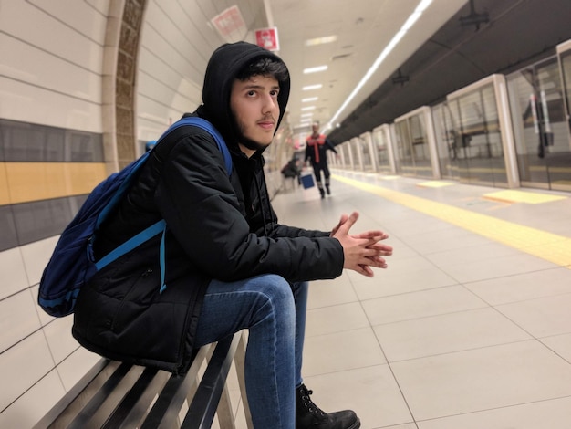 기차역 의 벤치 에 앉아 있는 젊은 남자 의 면