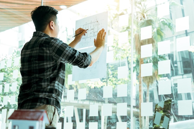 Photo side view of young man standing against window