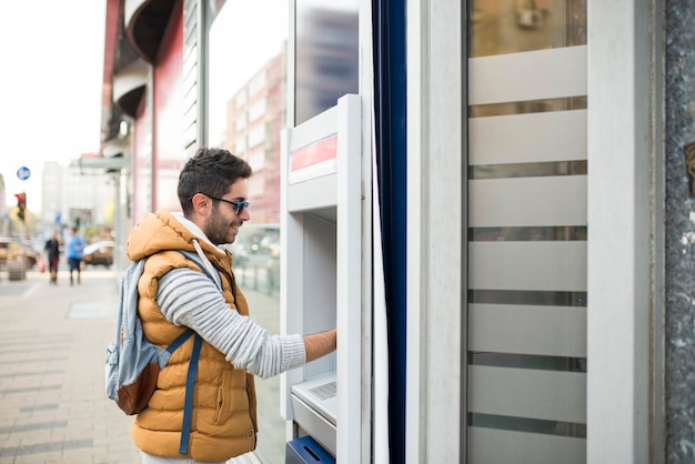 side view of young man using atm in city