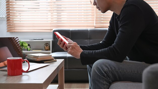 Side view young man using mobile phone on sofa