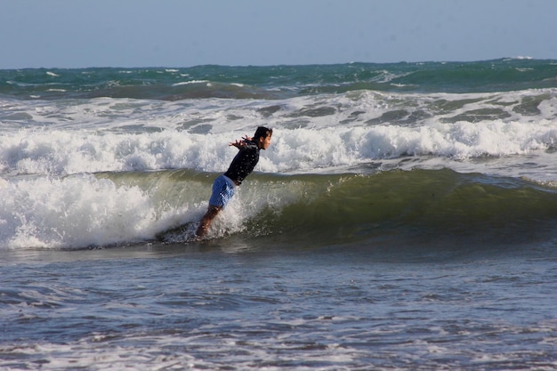 Side view of young man with arms outstretched swimming in sea against sky