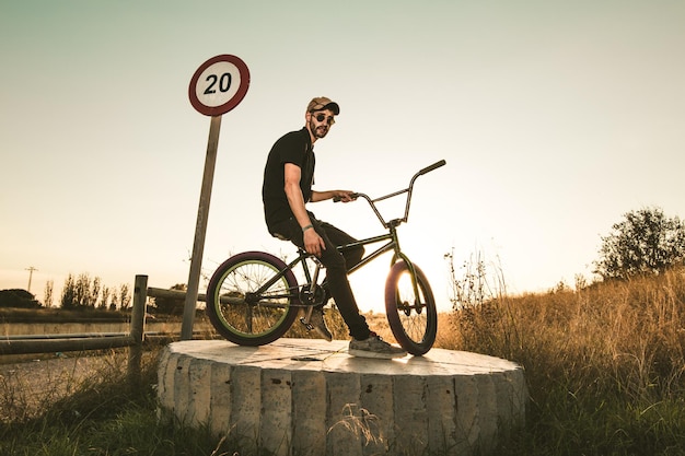 Photo side view of young man with bicycle against clear sky during sunset