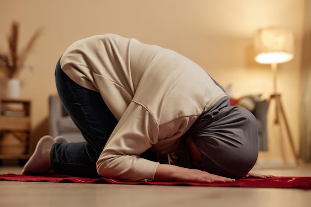 Side view of young muslim woman in traditional hijab bending forwards