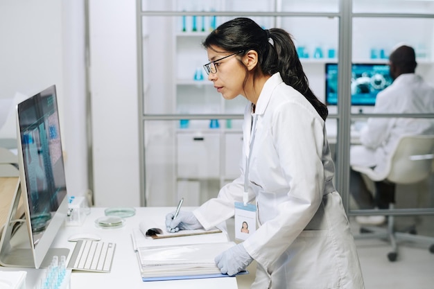 Vista laterale di una giovane dottoressa seria che guarda lo schermo del computer