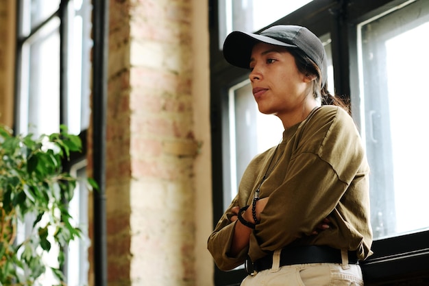 Side view of young upset woman with post traumatic syndrome standing by window