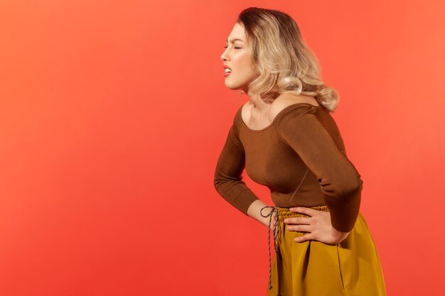 Side view of young woman against red background