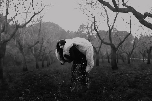 side view of young woman carrying teddy bear while walking on field against sky