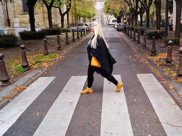 side view of young woman crossing road in city