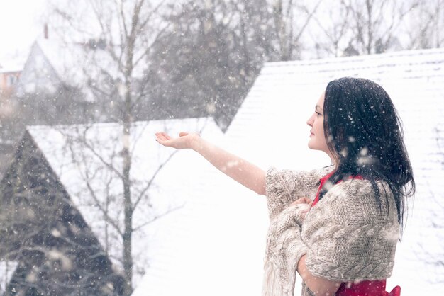 Photo side view of young woman enjoying snowfall