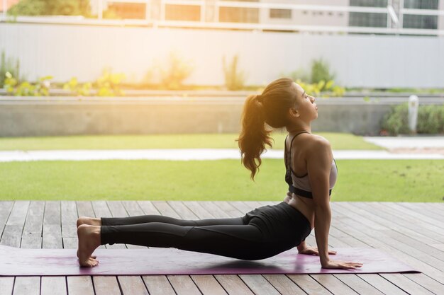 Photo side view of young woman exercising on boardwalk