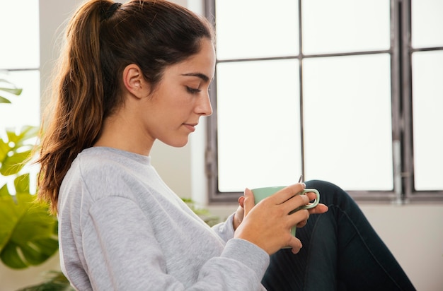 Side view of young woman having coffee at home