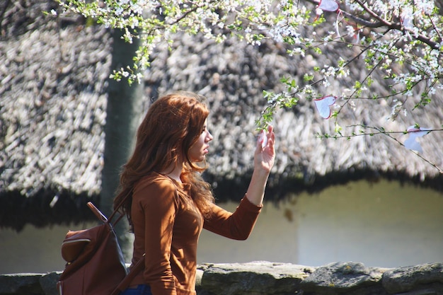 Side view of young woman holding heart shape labels on tree