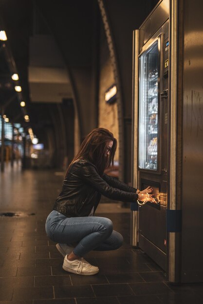 Side view of young woman holding illuminated string light while opening refrigerator in store at night