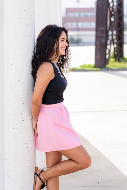 Photo side view of young woman leaning on architectural column