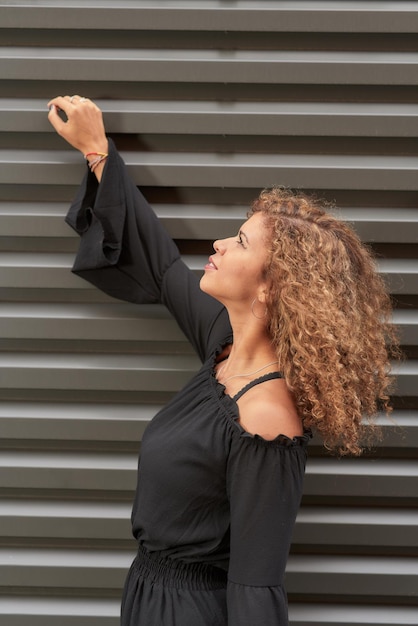 Photo side view of young woman looking up while standing against wall