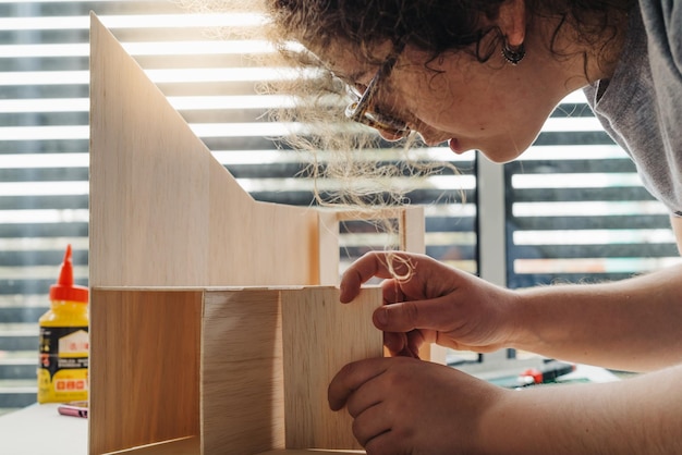 Foto vista laterale di una giovane donna che costruisce un modello di casa sul tavolo