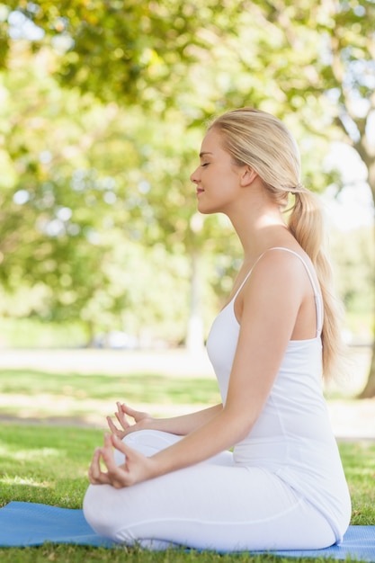 Side view of young woman meditating sitting on an exercise mat