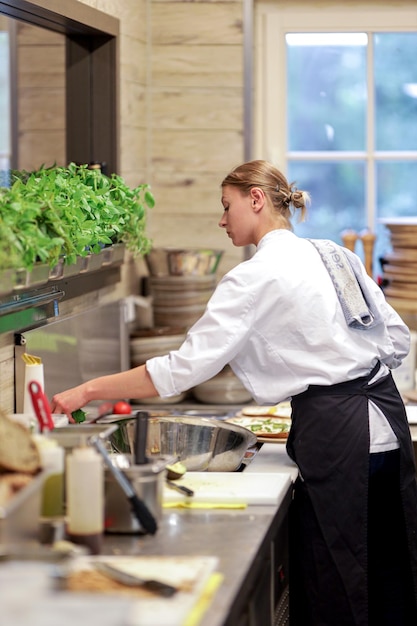 Side view of young woman preparing food in kitchen