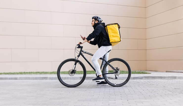 Photo side view of young woman riding bicycle against wall